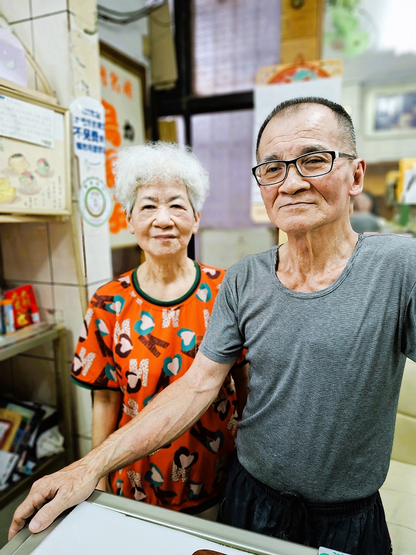 1._百珍麵包蛋糕由張錫本與張蔡貴夫婦合力經營,兩人也是店內的活招牌。(張耘書拍攝) (1) 1._百珍麵包蛋糕由張錫本與張蔡貴夫婦合力經營,兩人也是店內的活招牌。(張耘書拍攝) (1)